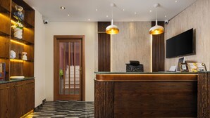 Un mostrador de recepción con detalles de madera, un televisor de pantalla plana e iluminación colgante.