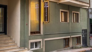 Un edificio de varios pisos con fachada verde, múltiples ventanas y una entrada visible con escalones.
