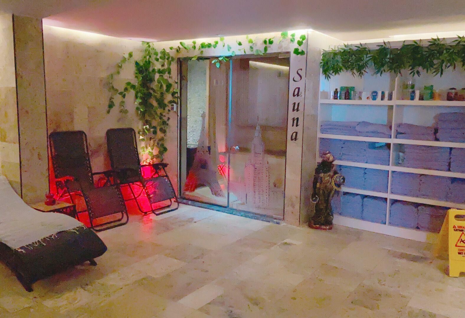Una sala de sauna con dos sillas, una estatua y estantes con toallas.