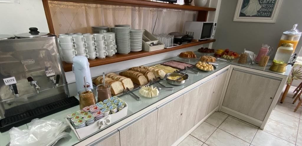 A buffet counter with various food items, a coffee station, and stacked plates and cups.