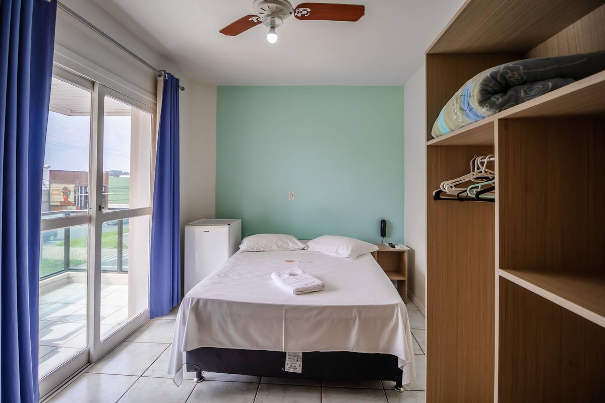 Une chambre à coucher avec un lit, une armoire, un ventilateur de plafond et une vue par la fenêtre.