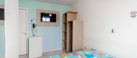 A bedroom with a bed, a TV mounted on the wall, a wardrobe, and a ceiling fan.