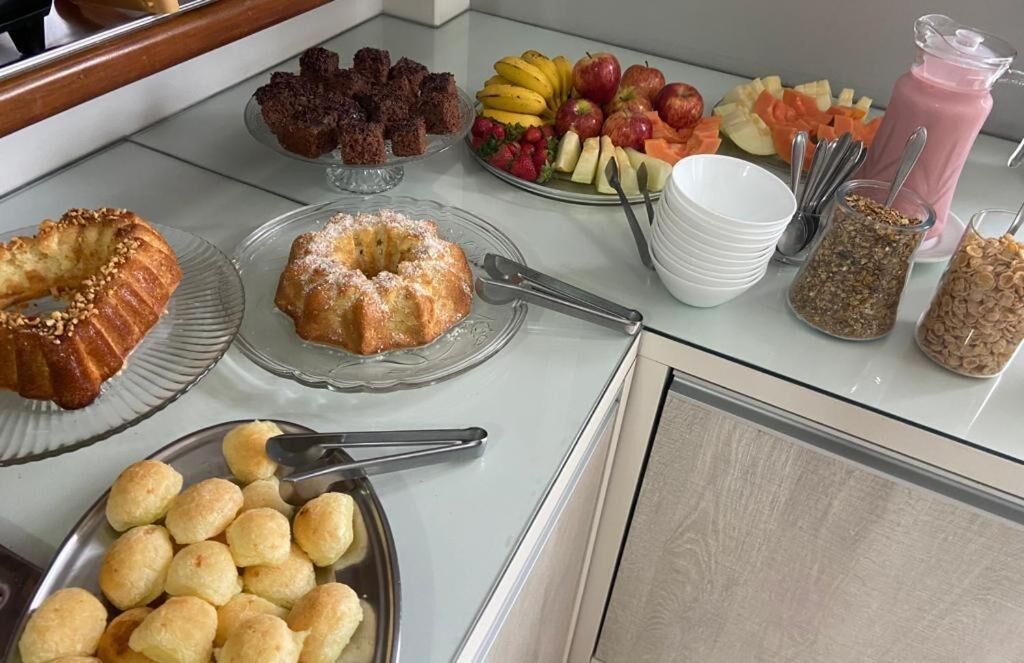 Una mesa de buffet con diversos alimentos, incluyendo pasteles, frutas y un batido rosa.
