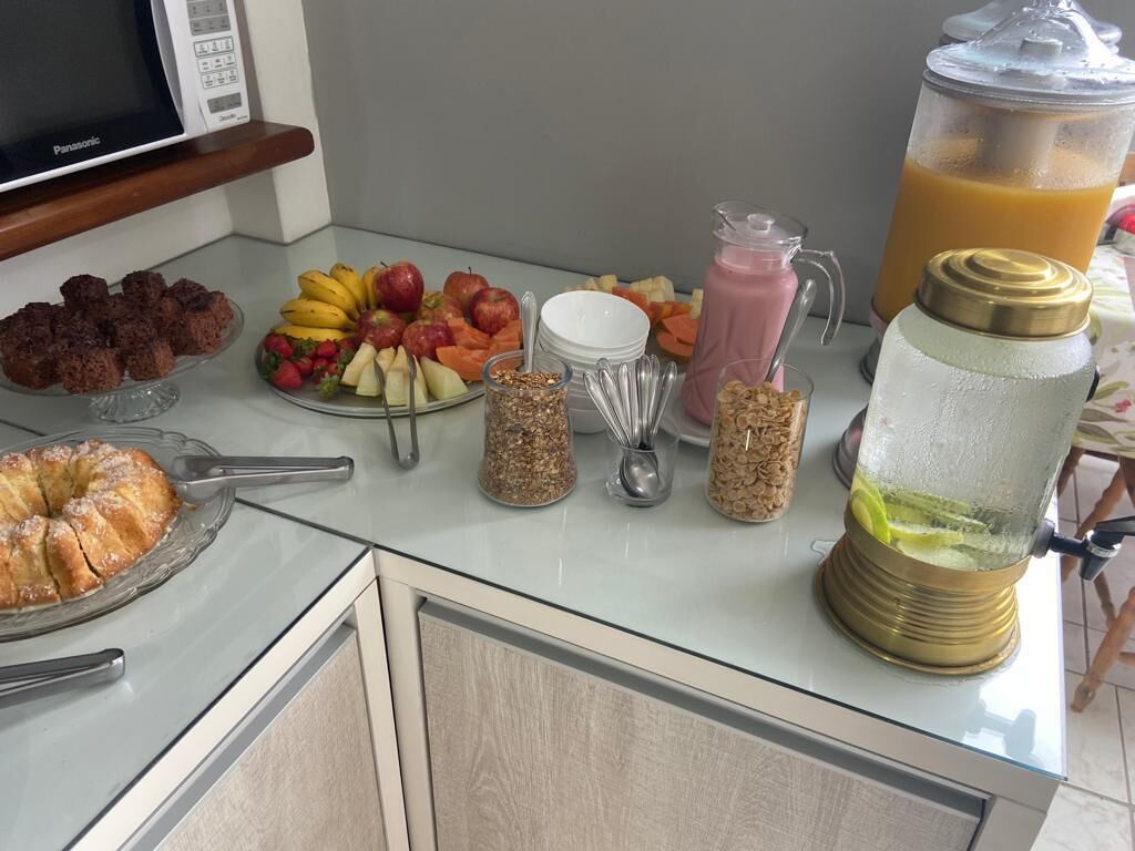 Preparación para el desayuno con frutas, una licuadora y un pastel sobre la encimera de la cocina.
