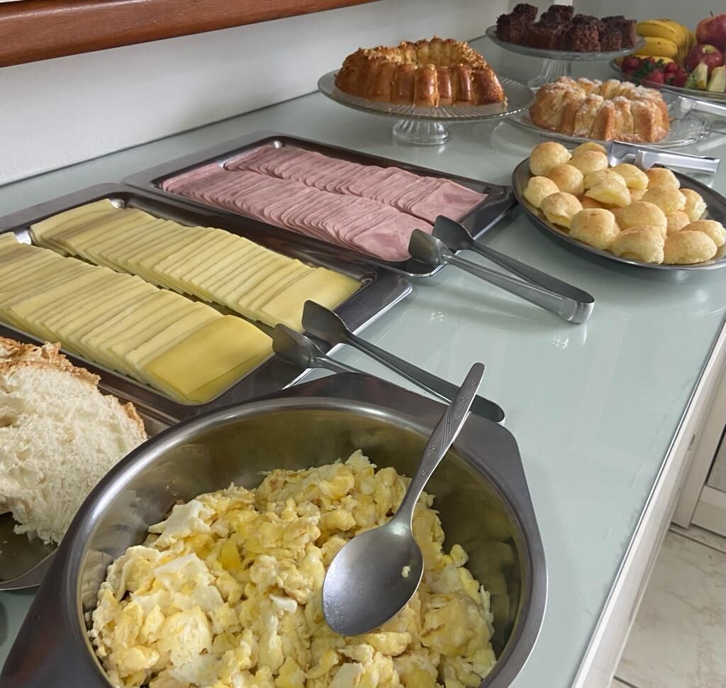 Buffet com diversos alimentos, incluindo ovos mexidos, pastelaria e sobremesas.