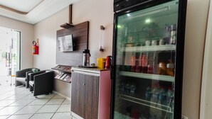 Une cuisine moderne équipée d’un réfrigérateur, d’une machine à café et d’un four à micro-ondes. On y trouve des chaises noires et un petit comptoir.