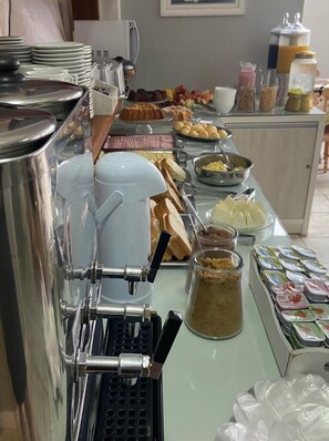 Een buffetopstelling met diverse gerechten, een koffieapparaat en toevoegingen.