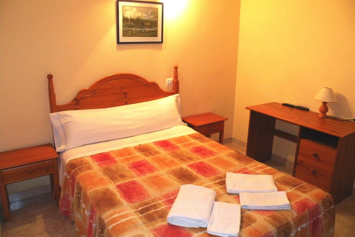 A neatly made bed with a plaid bedspread and two folded towels on it.