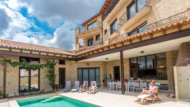 Ein zweistöckiges Gebäude mit Pool, Außenbereich und überdachter Terrasse.