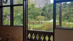 A room with large windows, a wooden floor, and a view of a mountainous landscape. - Pousada Pedra Azul (Domingos Martins)