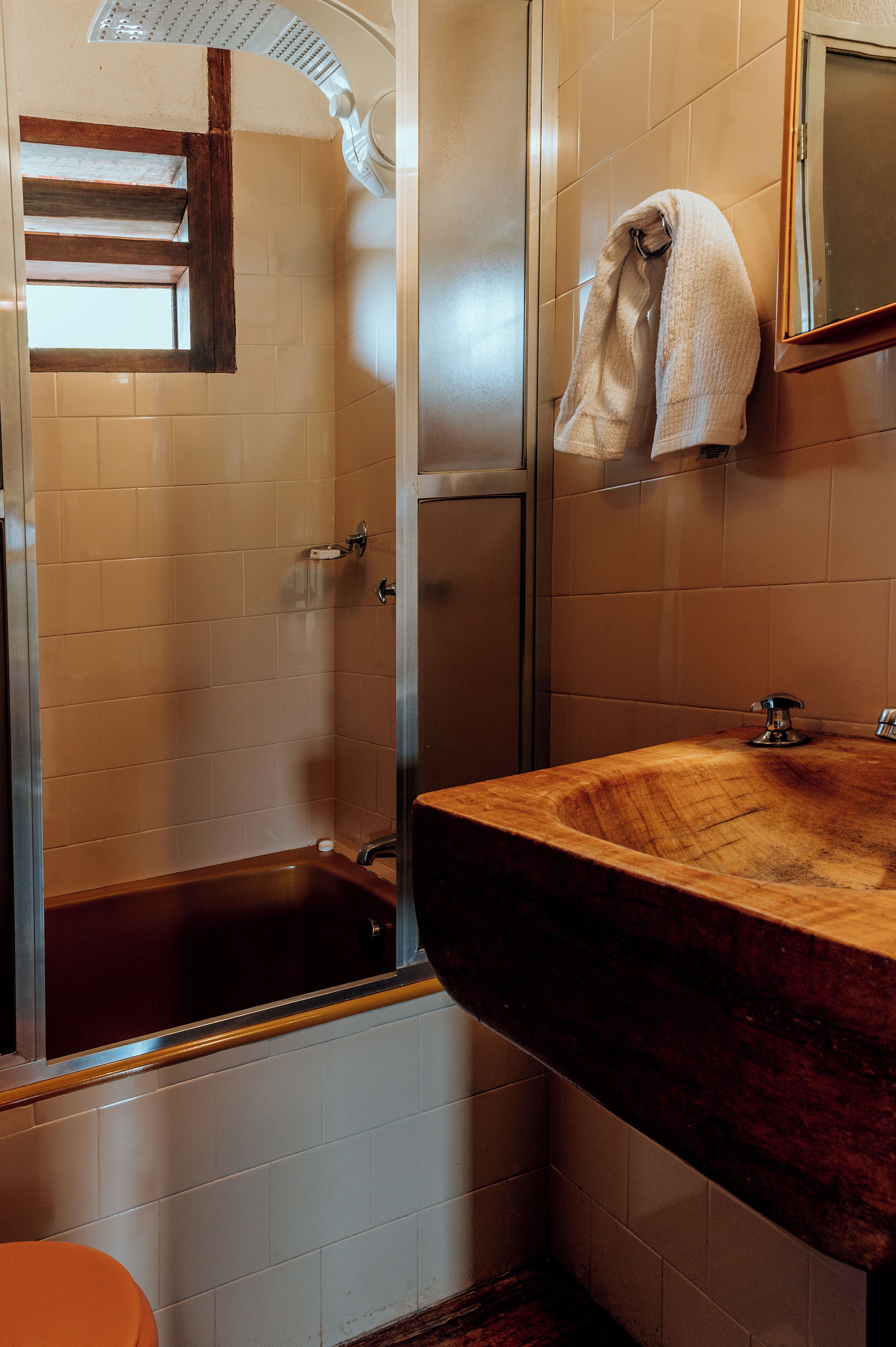 Un baño con tocador de madera, bañera y una toalla colgada en la pared.