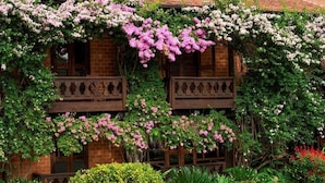 A building with a brick facade, wooden balconies, and flowering vines. - Pousada Pedra Azul (Domingos Martins)