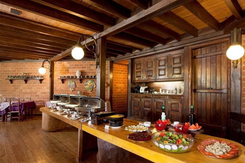 Ein rustikaler Essbereich mit einer langen Holztresen, einem Buffetsystem und Backsteinwänden.