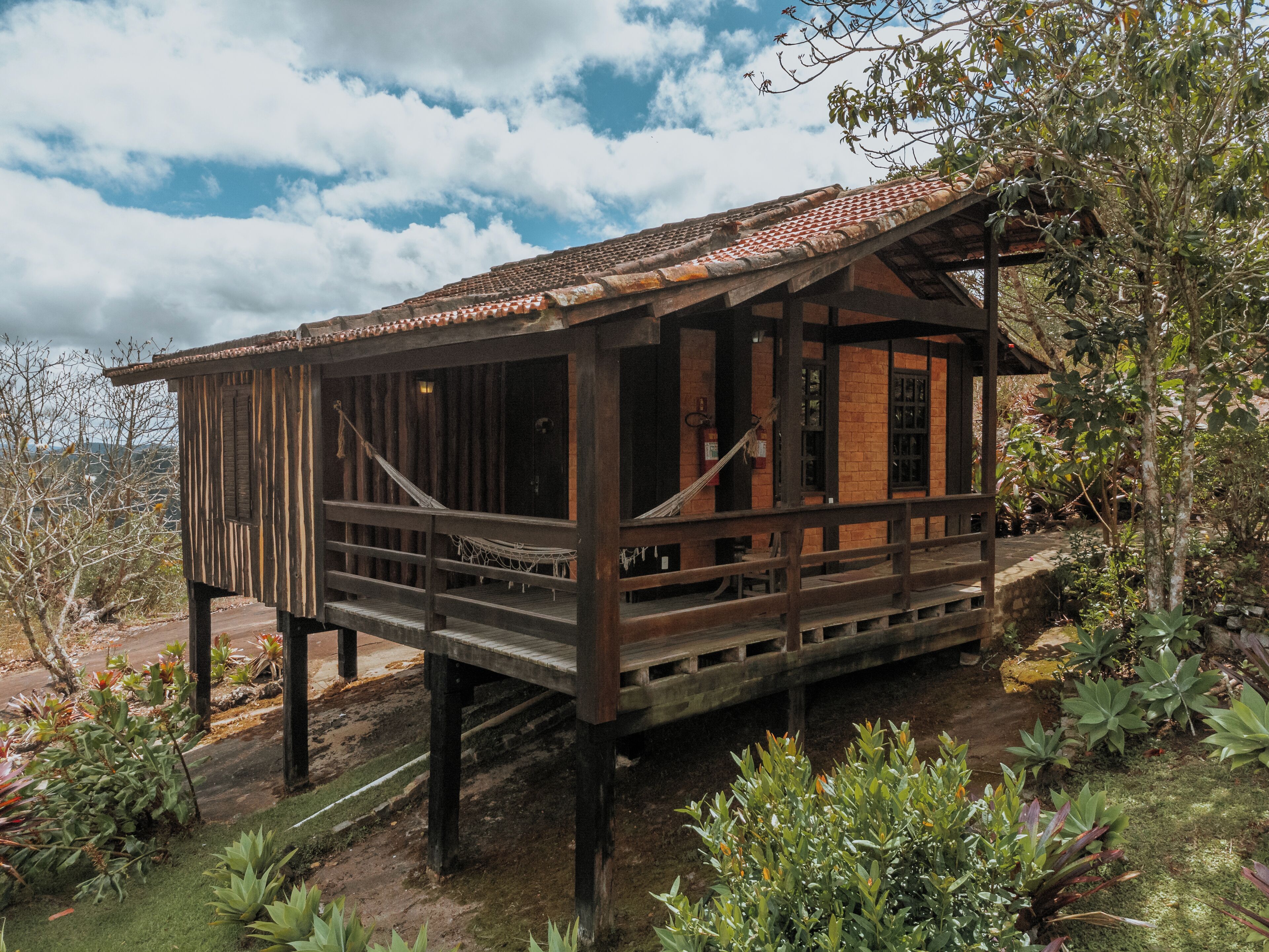 Une cabane en bois dotée d’un balcon, entourée d’une végétation luxuriante.