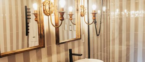 Un baño con tocador de madera, un espejo grande y un lavabo redondo.