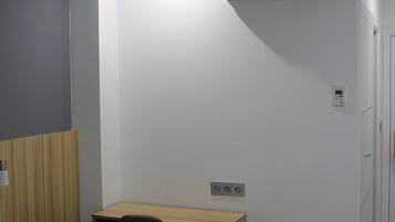 A hotel room with a bed, a desk, a chair, and a small table.