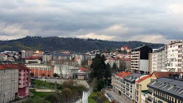 Un paisaje urbano con un río, edificios y una colina al fondo.