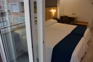 Habitación de hotel con dos camas, un escritorio y una silla.