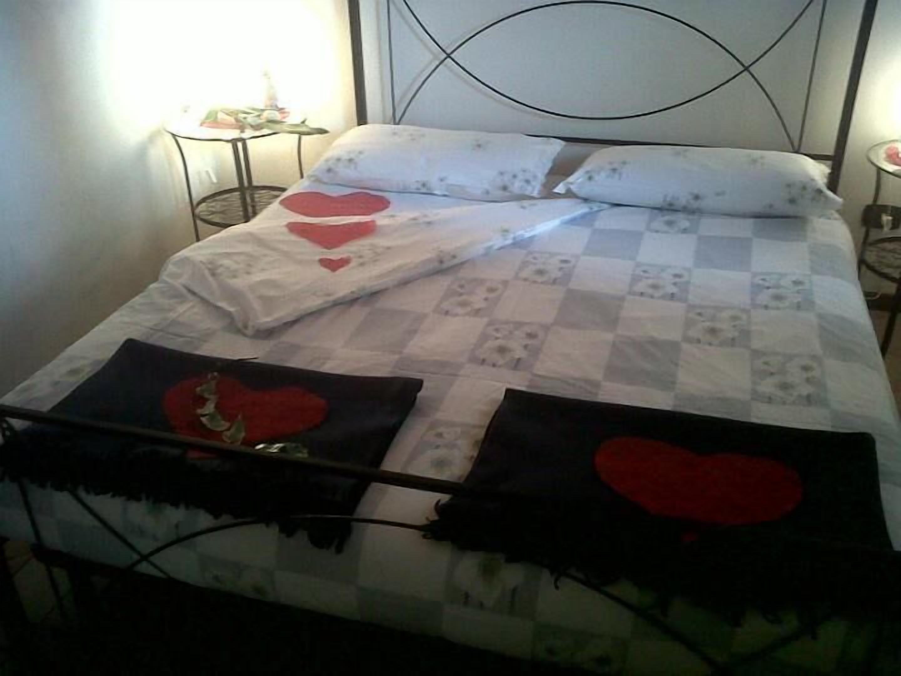 A bed with a checkered bedspread, pillows with heart designs, and a blanket with a heart design.