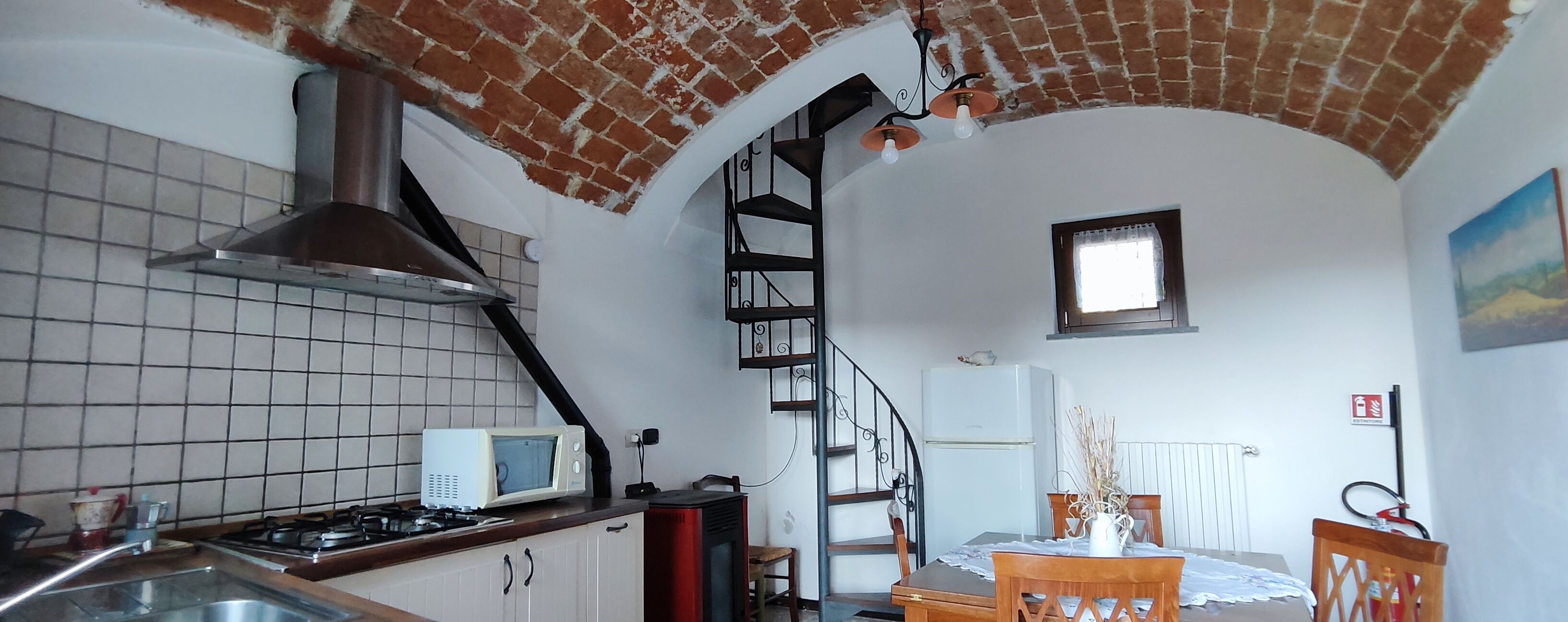 A kitchen with a tiled backsplash, a microwave, a gas stove, and a brick ceiling.