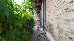 A narrow wooden pathway flanked by lush green foliage and a brick wall. - Cà Borgo Vecchio (Brusasco)