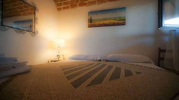 A cozy bedroom with a bed, a lamp, a painting, and a window.