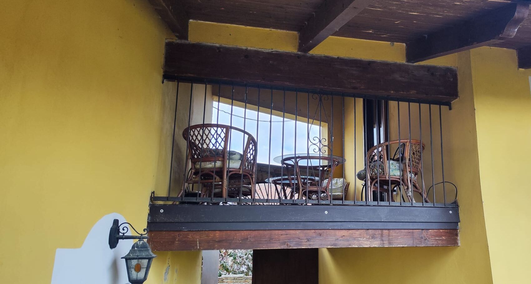 Un balcone con mobili in vimini e ringhiera in metallo.
