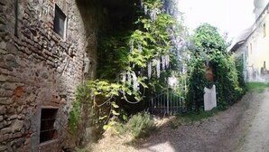 A narrow alleyway with stone walls, a dirt path, and greenery. - Cà Borgo Vecchio (Brusasco)