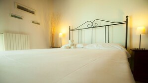 A neatly made bed with white linens, a black metal headboard, and two bedside lamps. - Cà Borgo Vecchio (Brusasco)