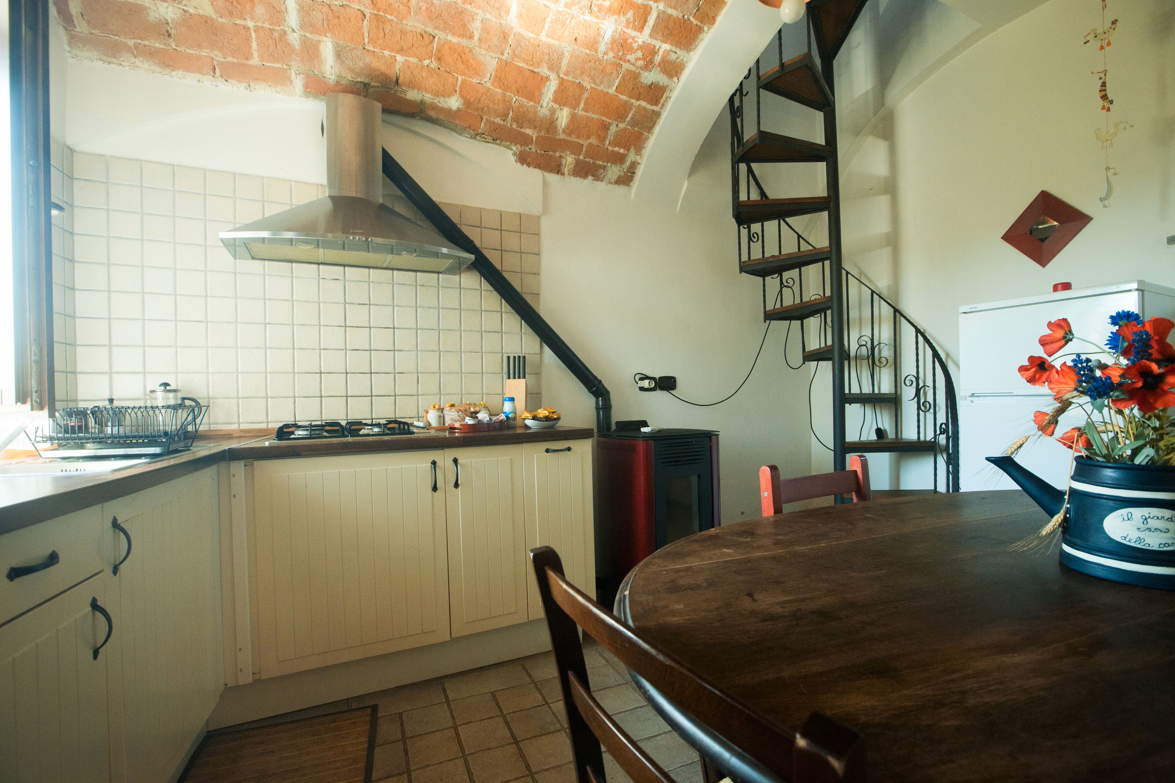 Una cocina con armarios blancos, techo de ladrillo y una mesa de comedor de madera.