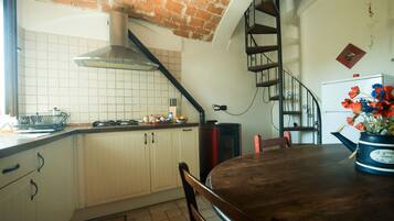 Una cocina con armarios blancos, techo de ladrillo y una mesa de comedor de madera.