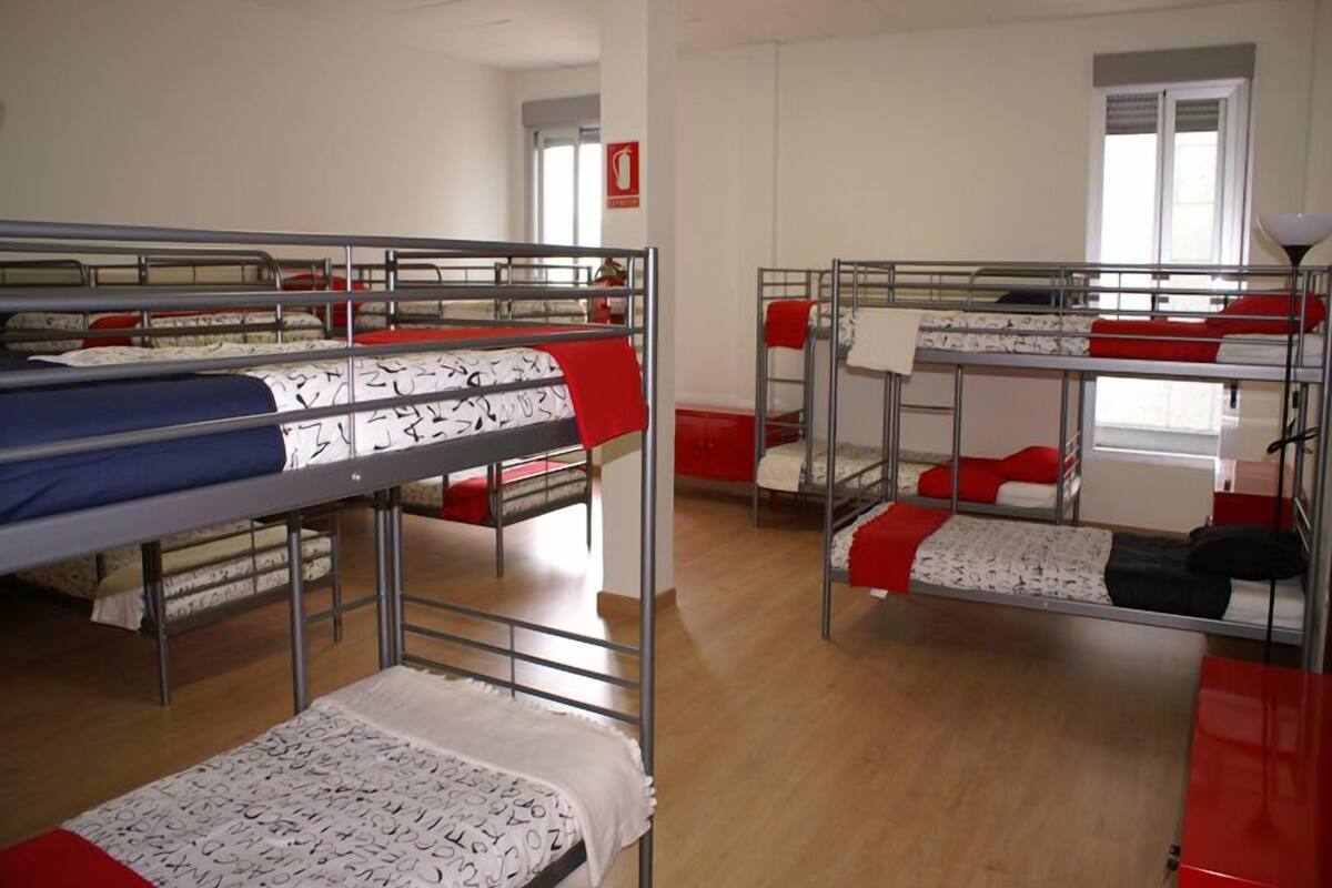 Un dormitorio con literas, un armario rojo y una ventana.