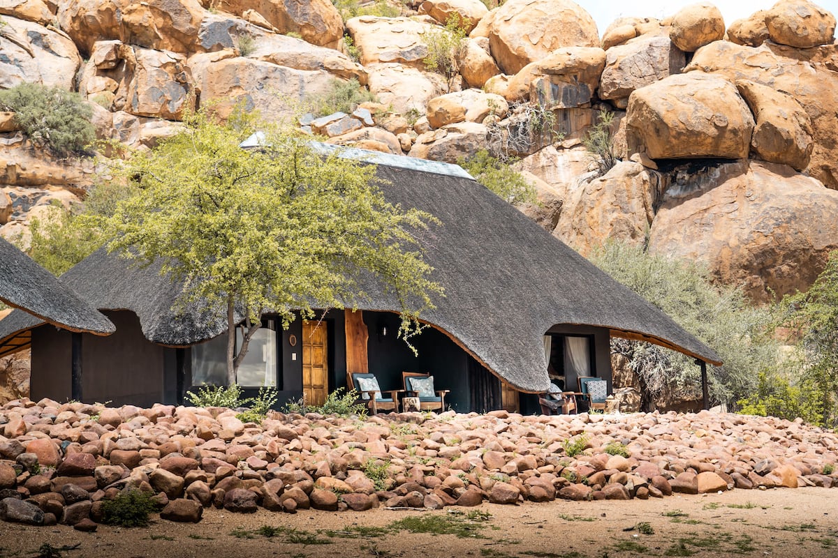A thatched-roof building with two wooden-framed windows and a stone foundation.