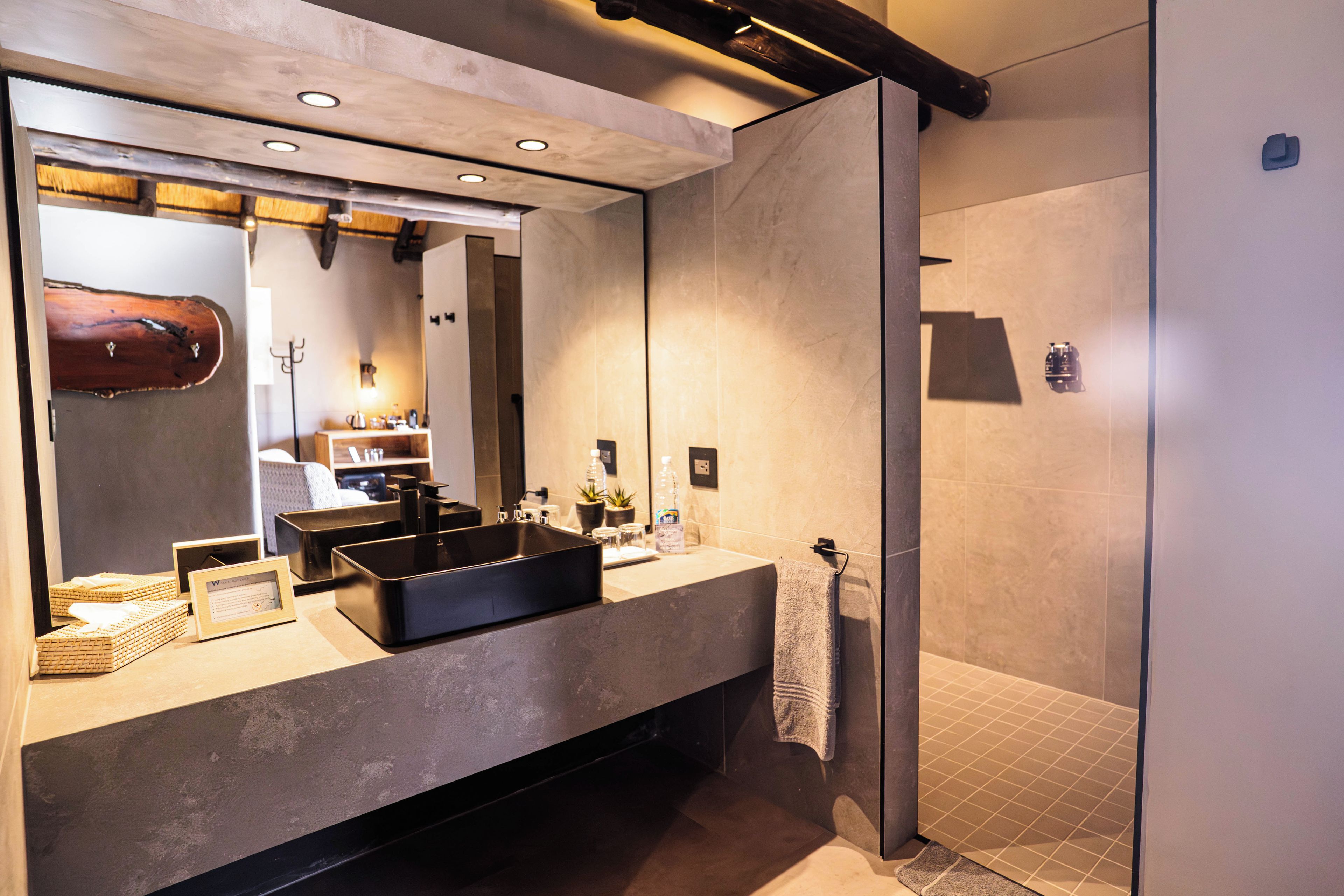 Een moderne badkamer met een grote spiegel, een zwarte wastafel en een inloopdouche.