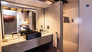 Een moderne badkamer met een grote spiegel, een zwarte wastafel en een inloopdouche.