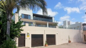 A two-story building with a flat roof, large windows, and a gated entrance. - 59LongSantos (Mossel Bay)