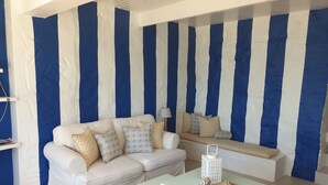 A room with a white sofa, patterned cushions, and a small table with decorative items. - 59LongSantos (Mossel Bay)
