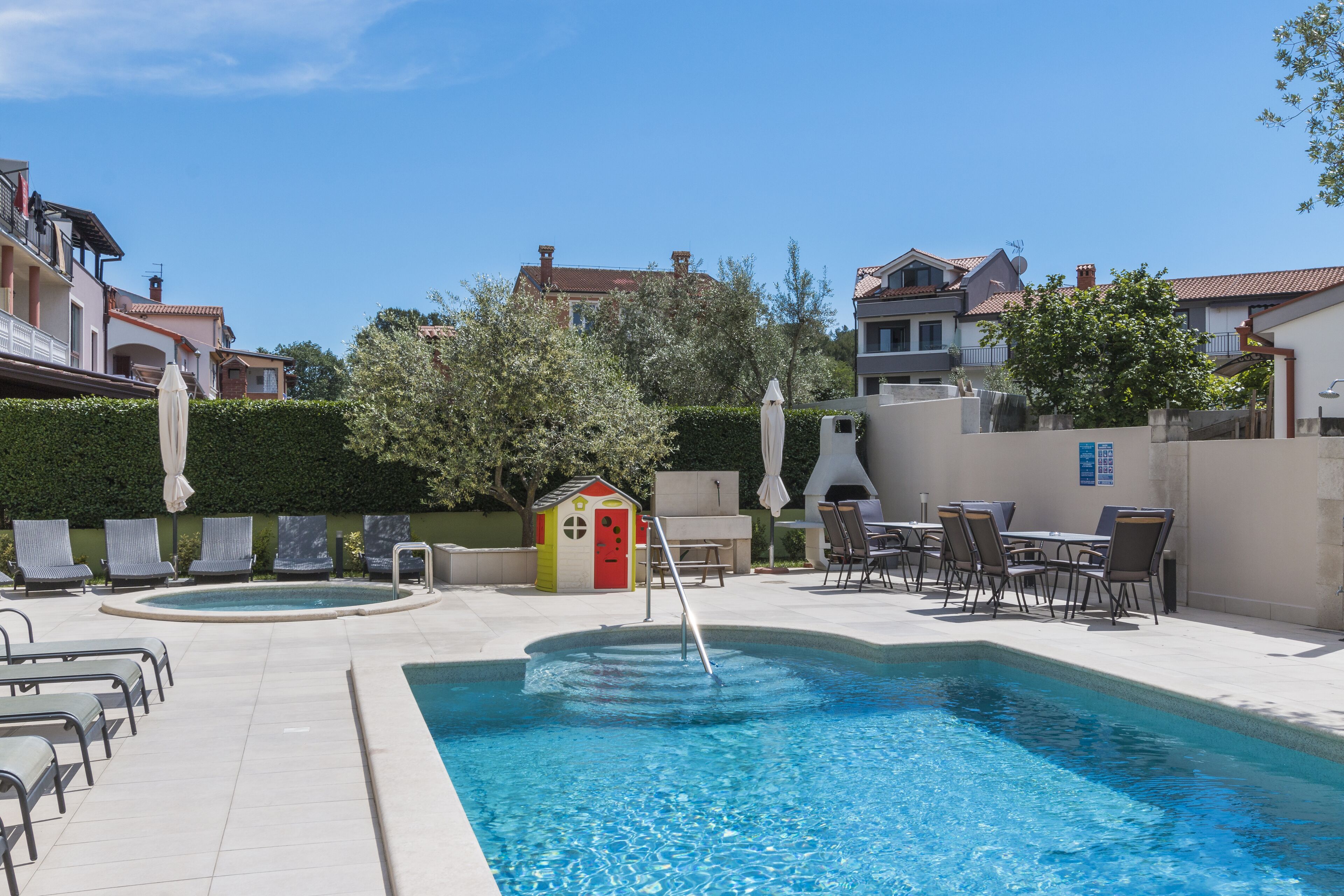 A swimming pool with lounge chairs and a small playhouse.