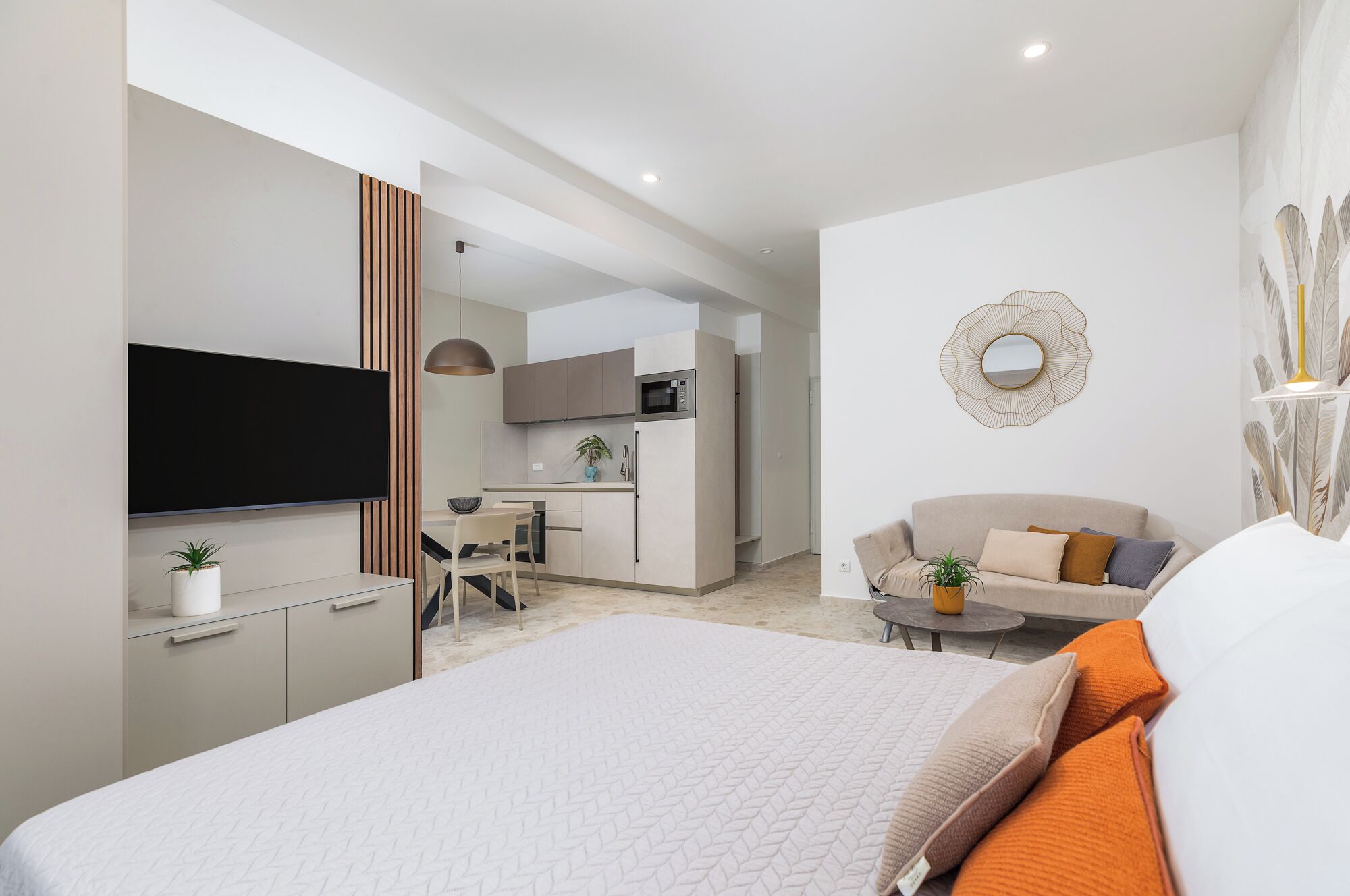 Moderni hotellihuone, jossa on suuri sänky, sohva, ruokailutila ja pieni keittiönurkkaus.