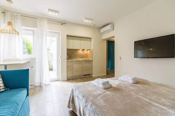 A modern bedroom with a bed, a TV, a bathroom, and a kitchenette. - Villa Nina Apartments (Fazana)
