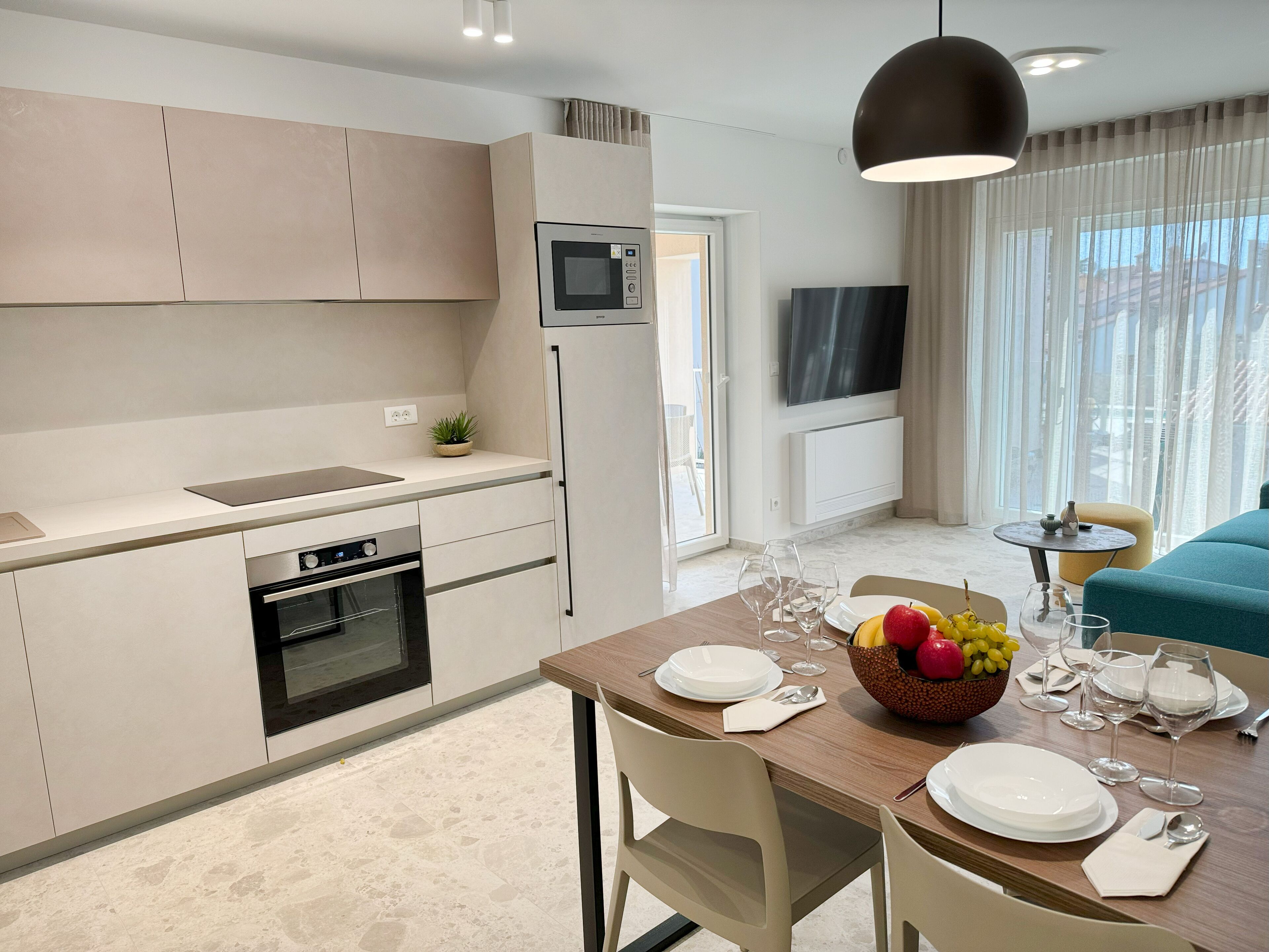A modern kitchen with a built-in oven, microwave, and a dining area with a table set for four.