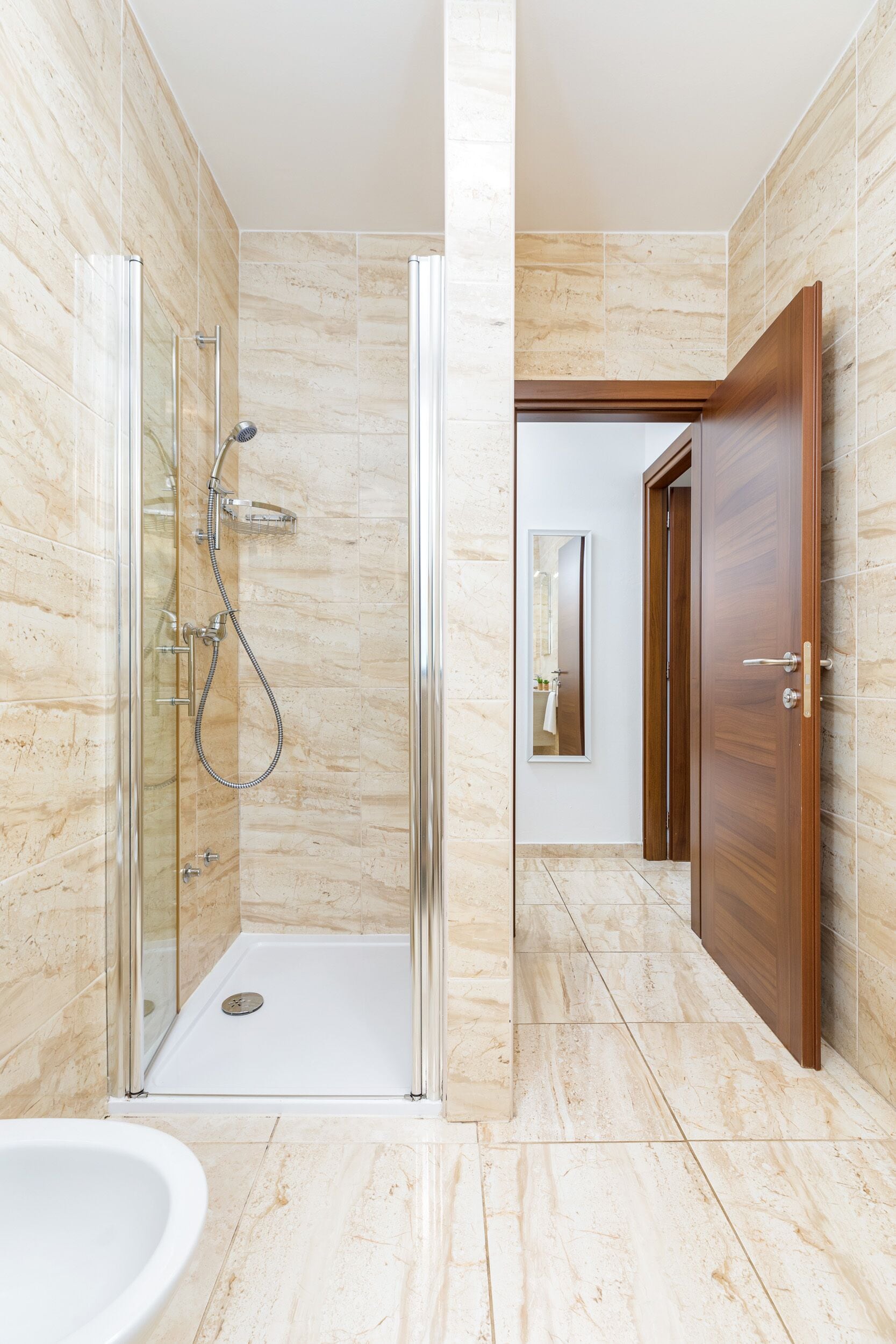 Une salle de bain moderne avec une douche à parois de verre, un lavabo et une porte en bois.