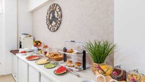 A buffet setup with various food items and a decorative wall clock.