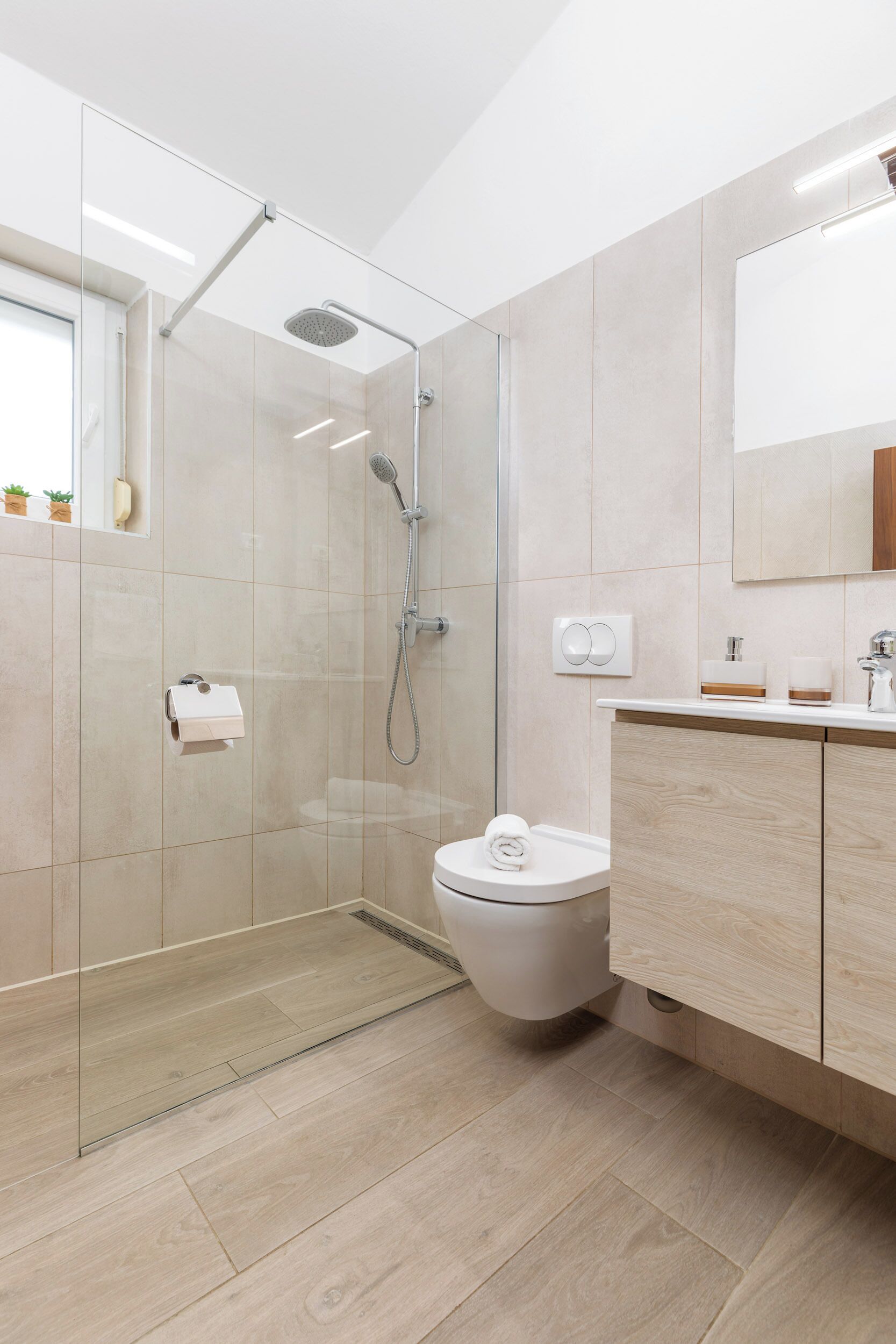 Une salle de bain moderne avec une douche à parois de verre, des toilettes et un meuble-lavabo avec un miroir.
