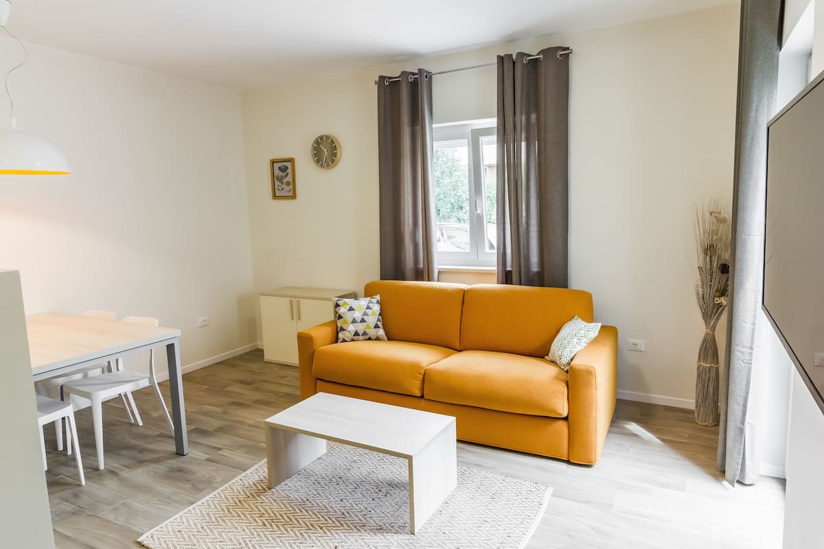 A modern living room with a sofa, coffee table, and dining area.