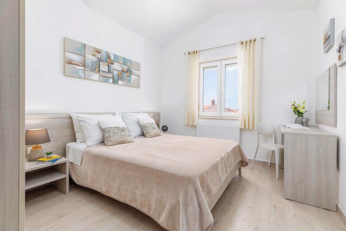 A modern bedroom with a large bed, bedside table, and a desk.