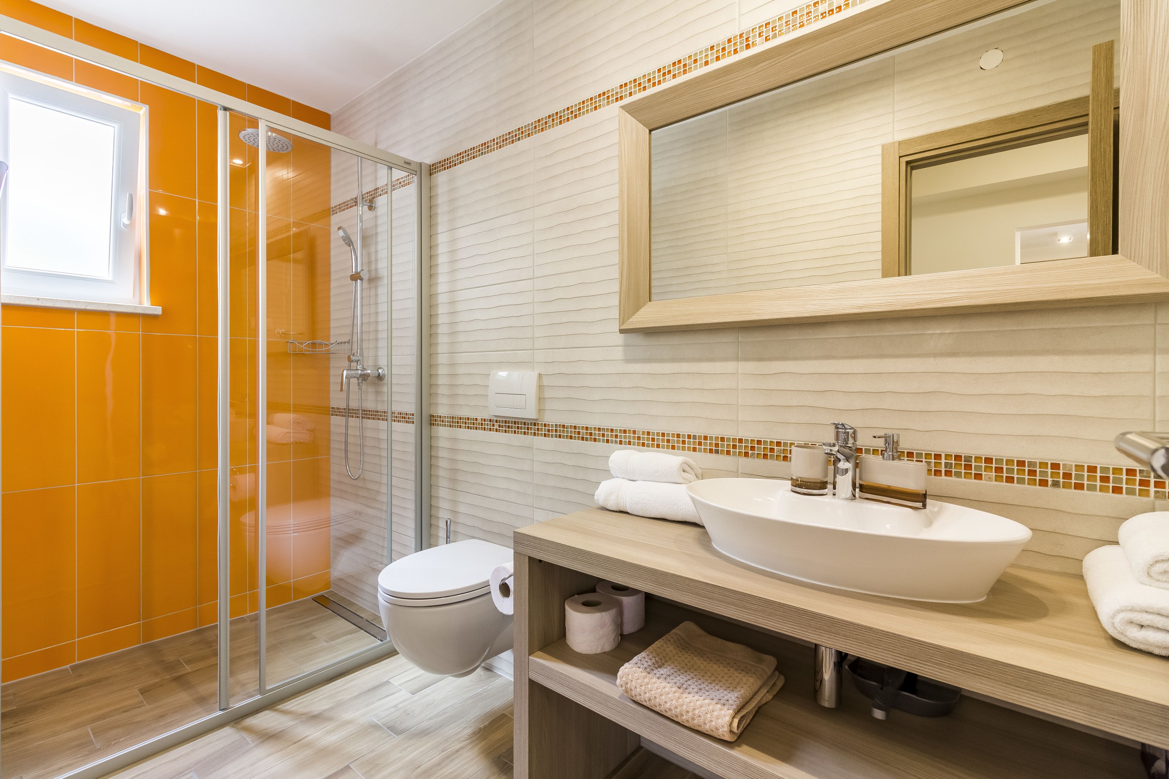 A modern bathroom with a glass-enclosed shower, a white sink, and a large mirror.