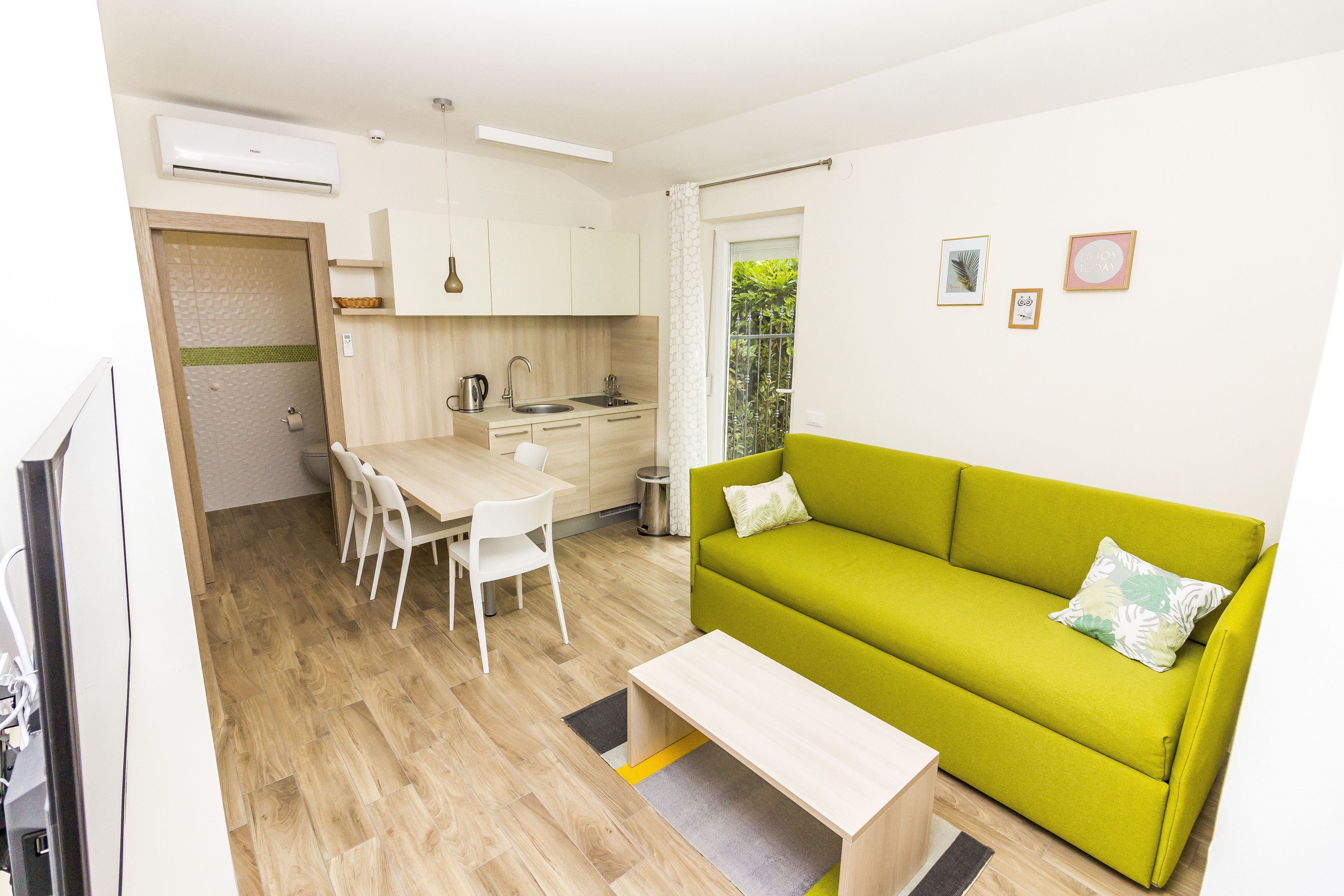 A compact living space with a kitchenette, a dining area, and a green sofa.