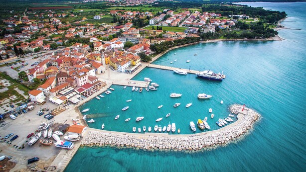 An aerial view of a coastal town with a marina, boats, and a mix of residential and commercial buildings.