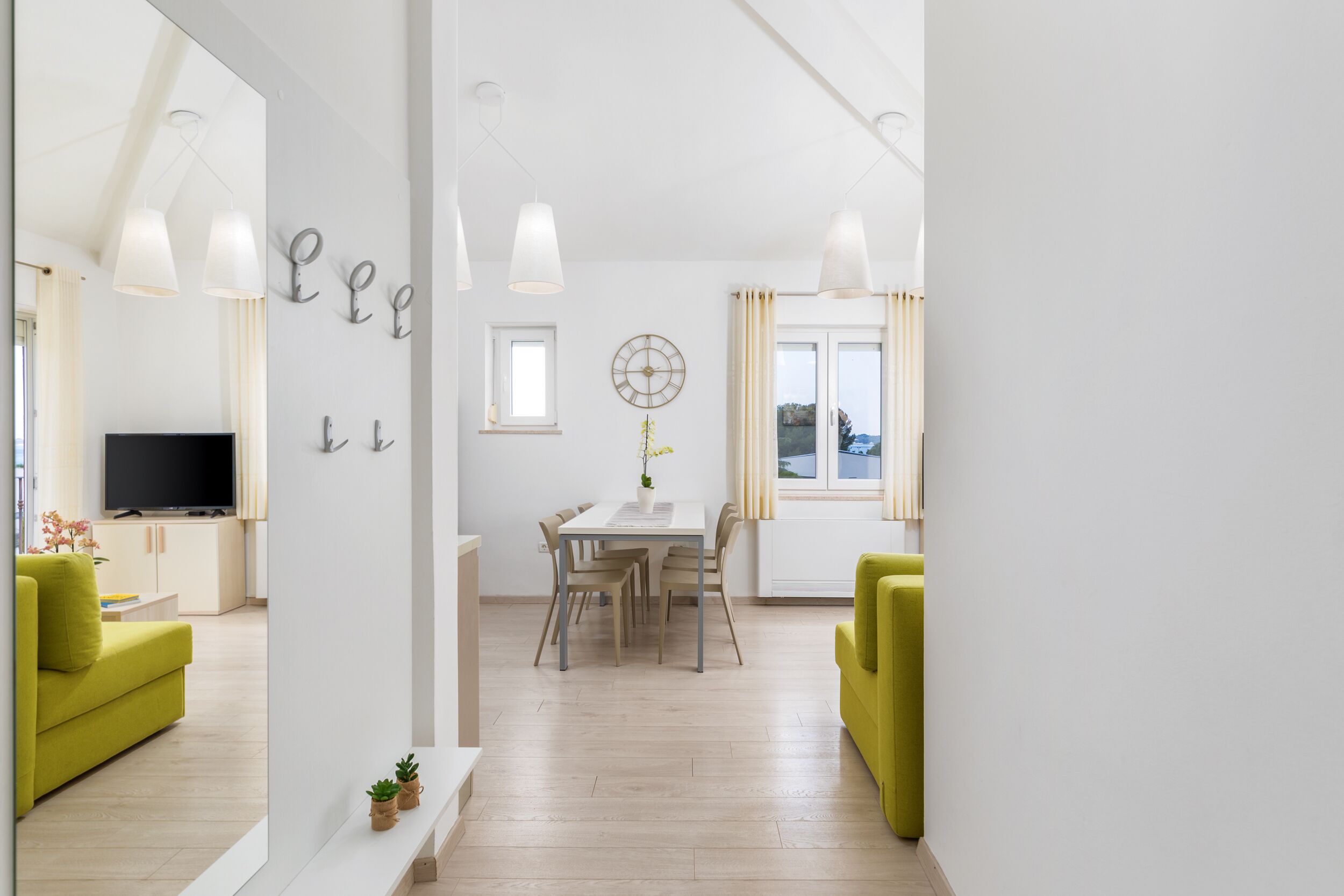 Un salon moderne avec un canapé, une table à manger et des chaises, ainsi qu’un téléviseur.